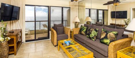 A living room with a sofa, two armchairs, a coffee table, and a TV.