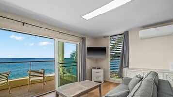 Deluxe Condo, 1 Bedroom, Oceanfront | Living room | 65-inch flat-screen TV with cable channels