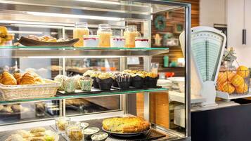 Bakery counter offering a variety of pastries, including croissants and muffins, with custom-sized options available.