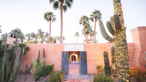 A desert garden with cacti and palm trees, a brick pathway, and a building entrance with an archway. - Royal Palms Resort and Spa, part of Hyatt (Phoenix)