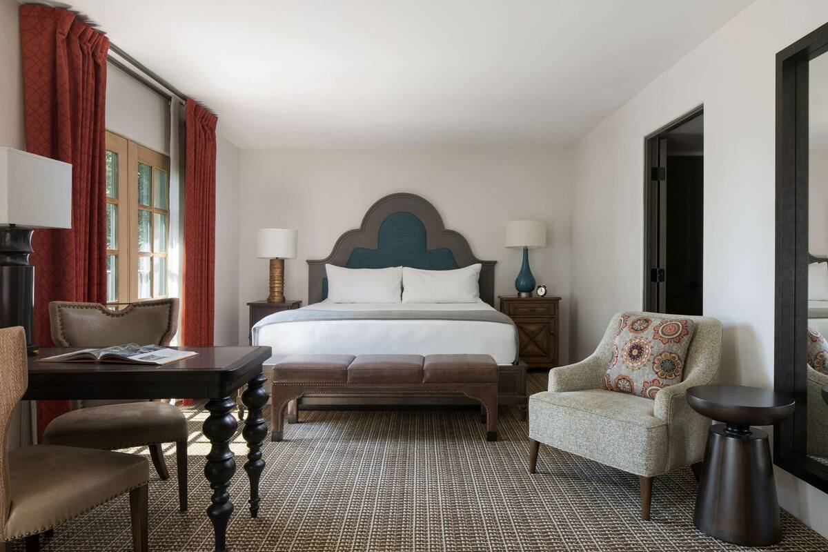 Ein Hotelzimmer mit Bett, Schreibtisch, Stuhl, Sofa und einem kleinen Tisch.