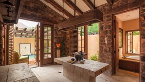 Habitación con piso de piedra, una isla grande, pared de piedra y vista a una piscina.