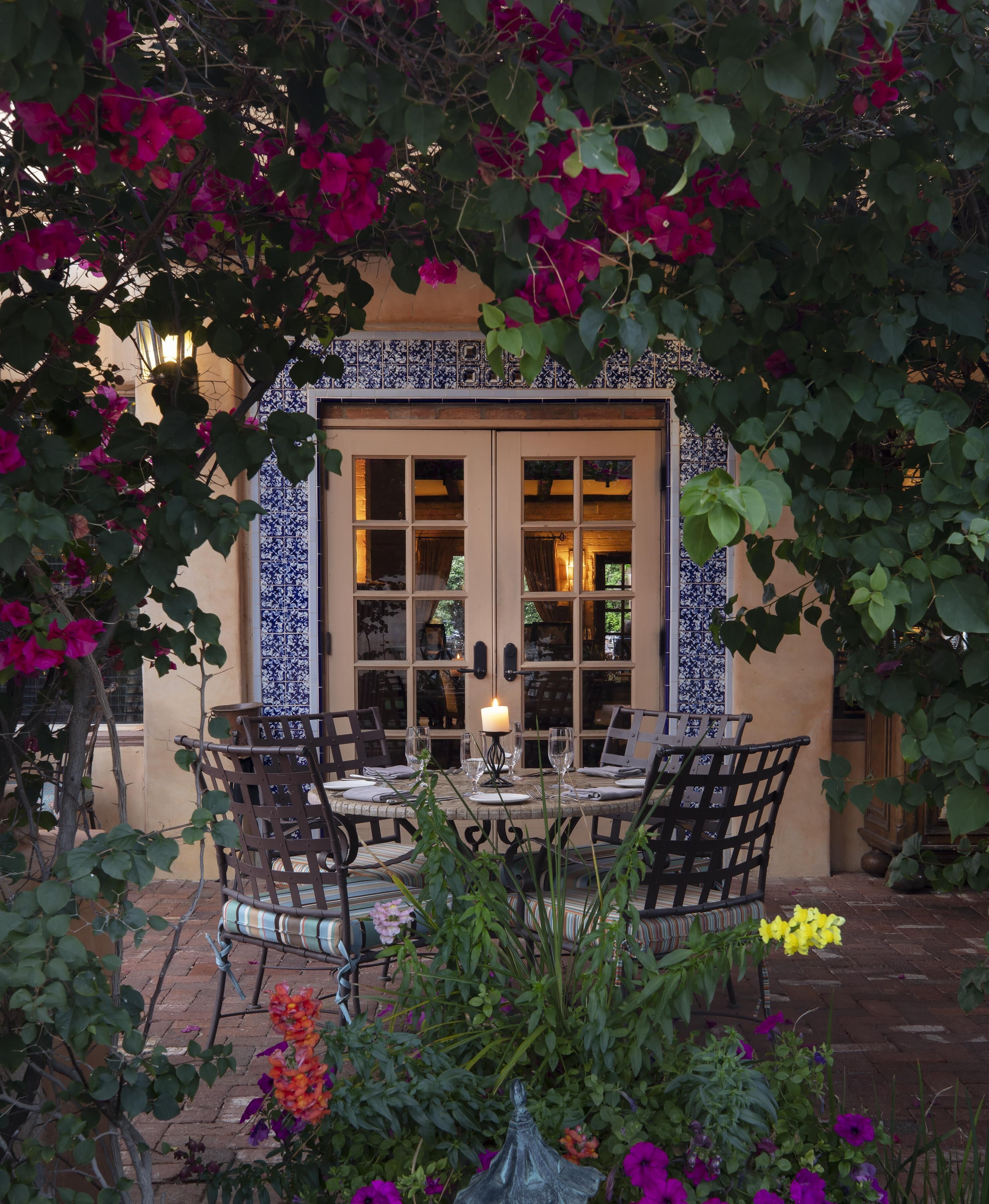 A patio with a table and chairs, a candle, and a view of a building with blue and white tiles.