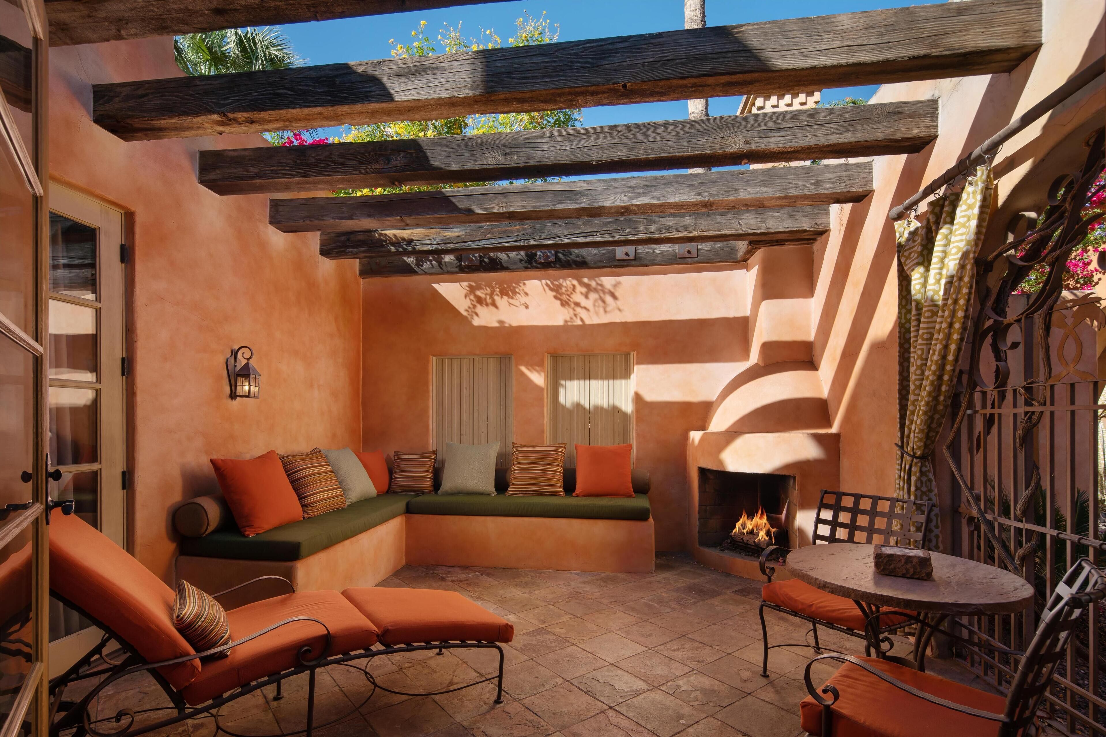 A cozy outdoor seating area with a fire pit, cushioned seating, and a table.