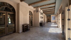 A spacious corridor with high ceilings, wooden beams, and large arched windows.