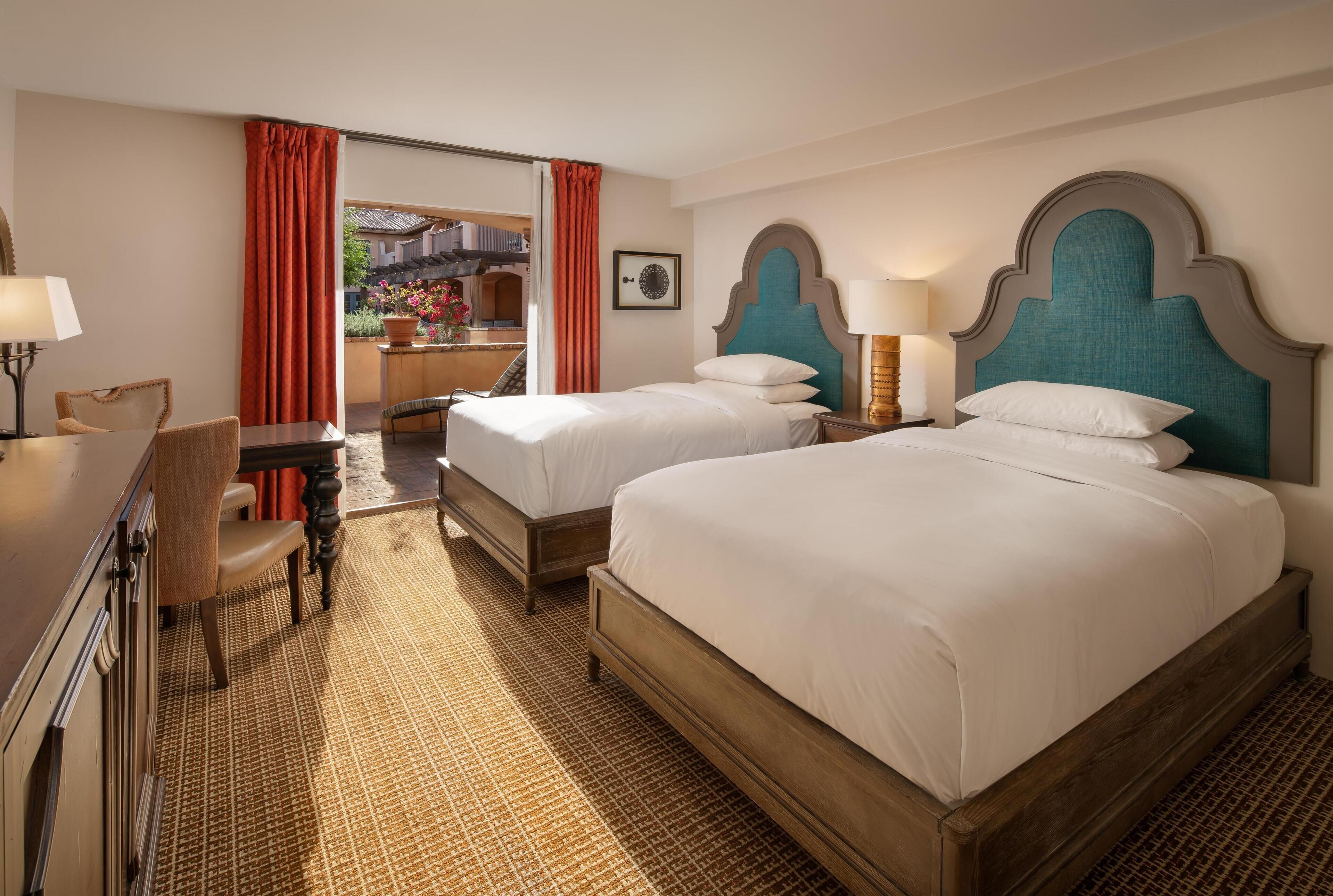 Ein Hotelzimmer mit zwei Betten, einem Schreibtisch und einem Sessel.
