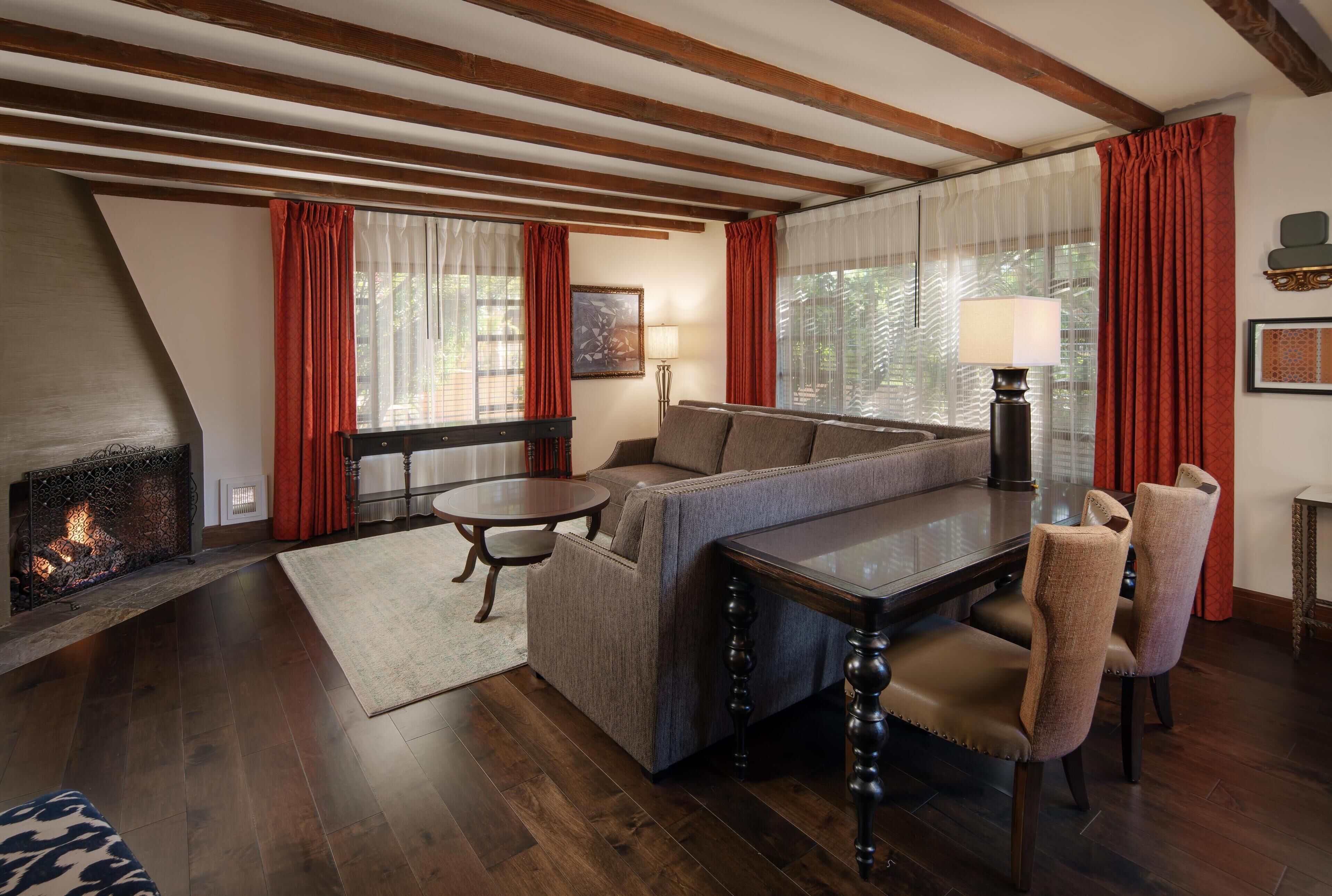 A cozy living room with a fireplace, a sofa, a dining table, and a lamp.