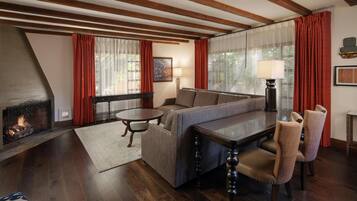 A cozy living room with a fireplace, a sofa, a dining table, and a lamp.