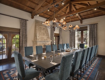 A room with a wooden table, blue sofa, patterned carpet, and a chandelier. at Royal Palms Resort and Spa, part of Hyatt