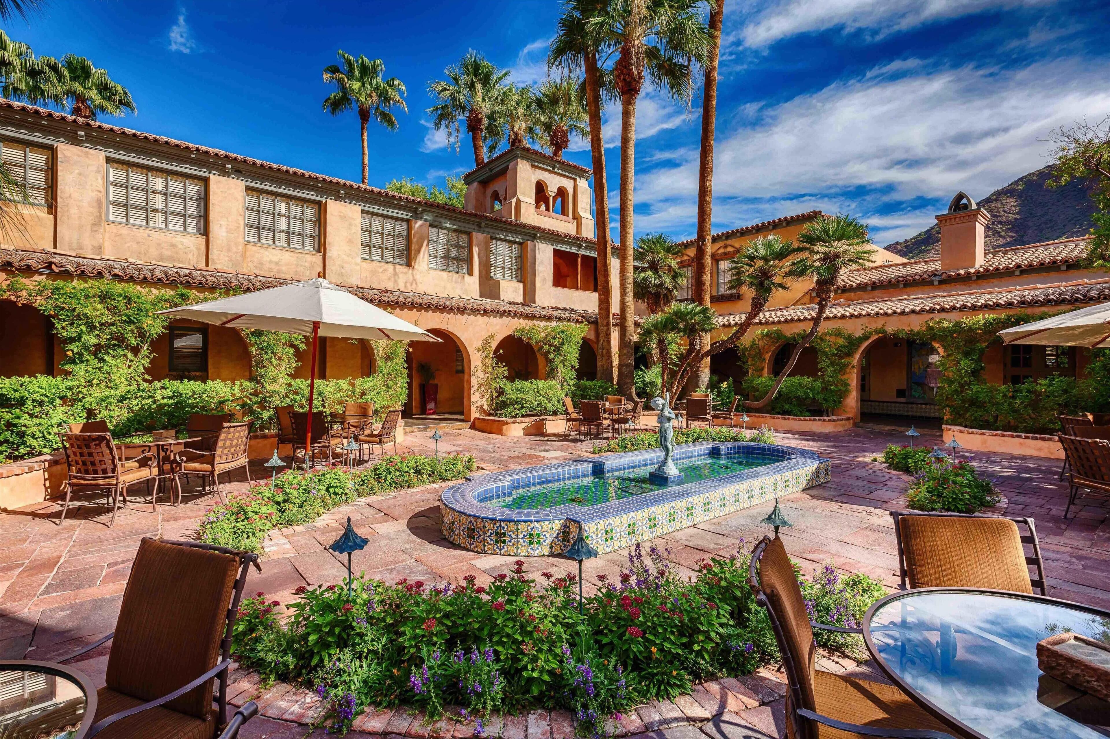 A courtyard with a pool, outdoor seating, and palm trees.