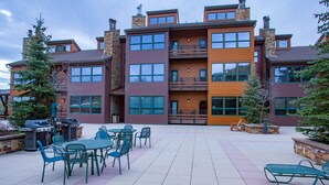 Un immeuble à plusieurs étages doté d’un patio comprenant un espace extérieur avec des sièges et un barbecue.