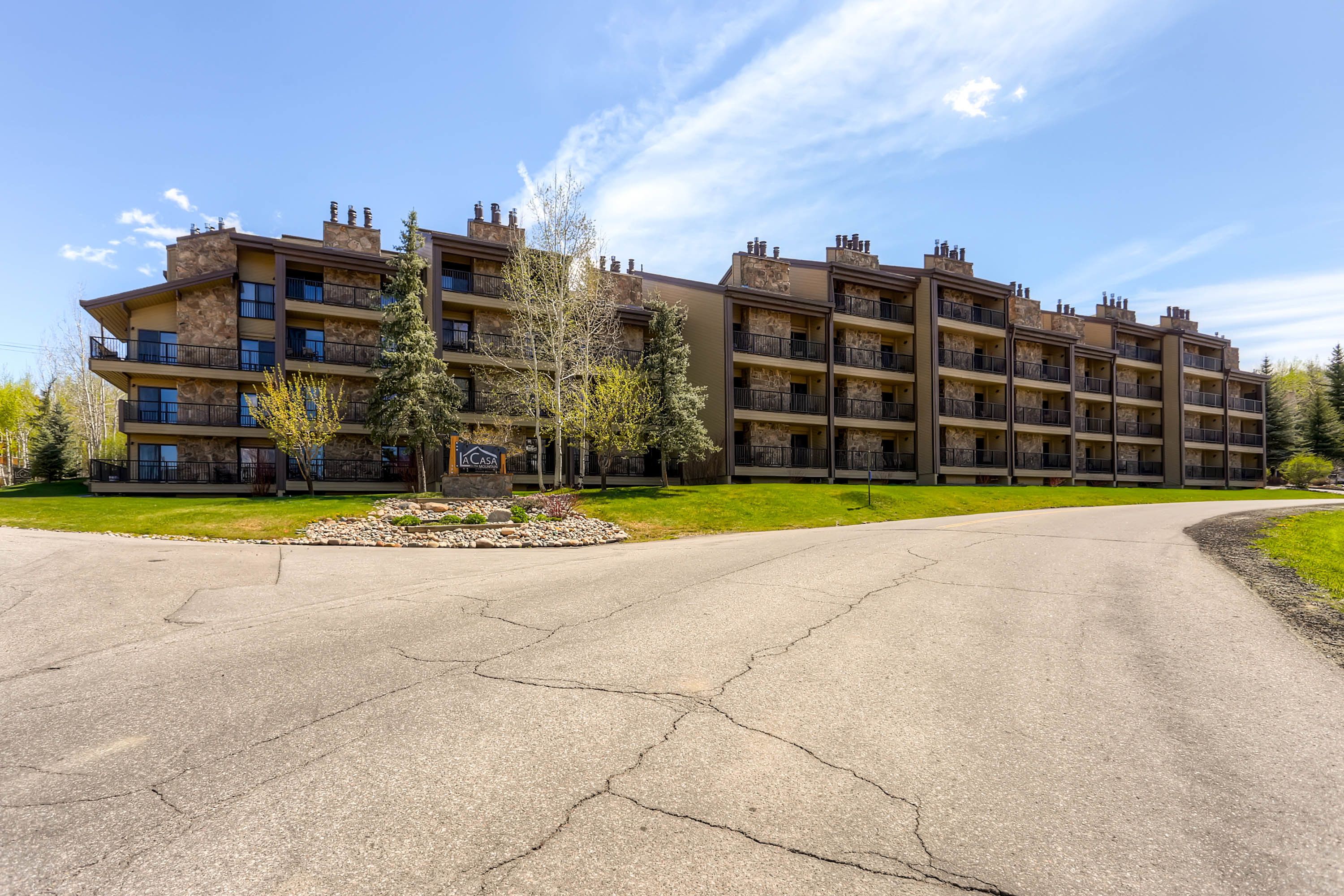 A multi-story hotel with balconies, a landscaped lawn, and a clear sky.