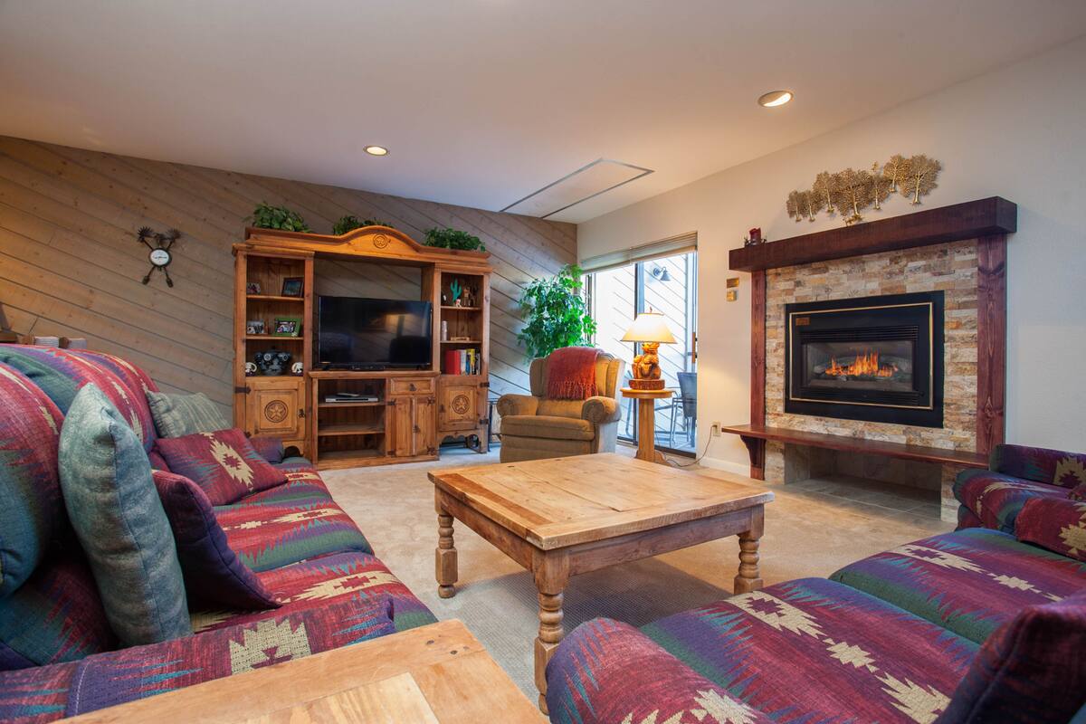 A cozy living room with a fireplace, a television, and a bookshelf.