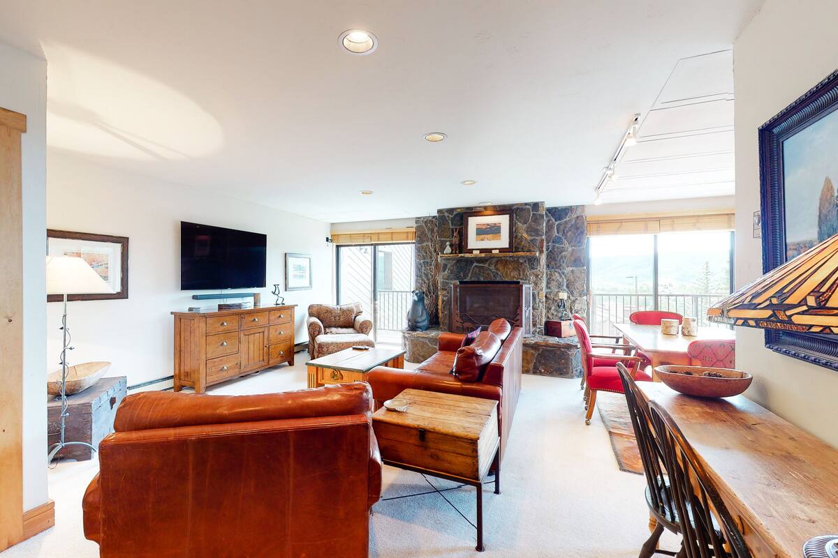 A spacious living room with a fireplace, leather sofas, a wooden coffee table, and a TV.
