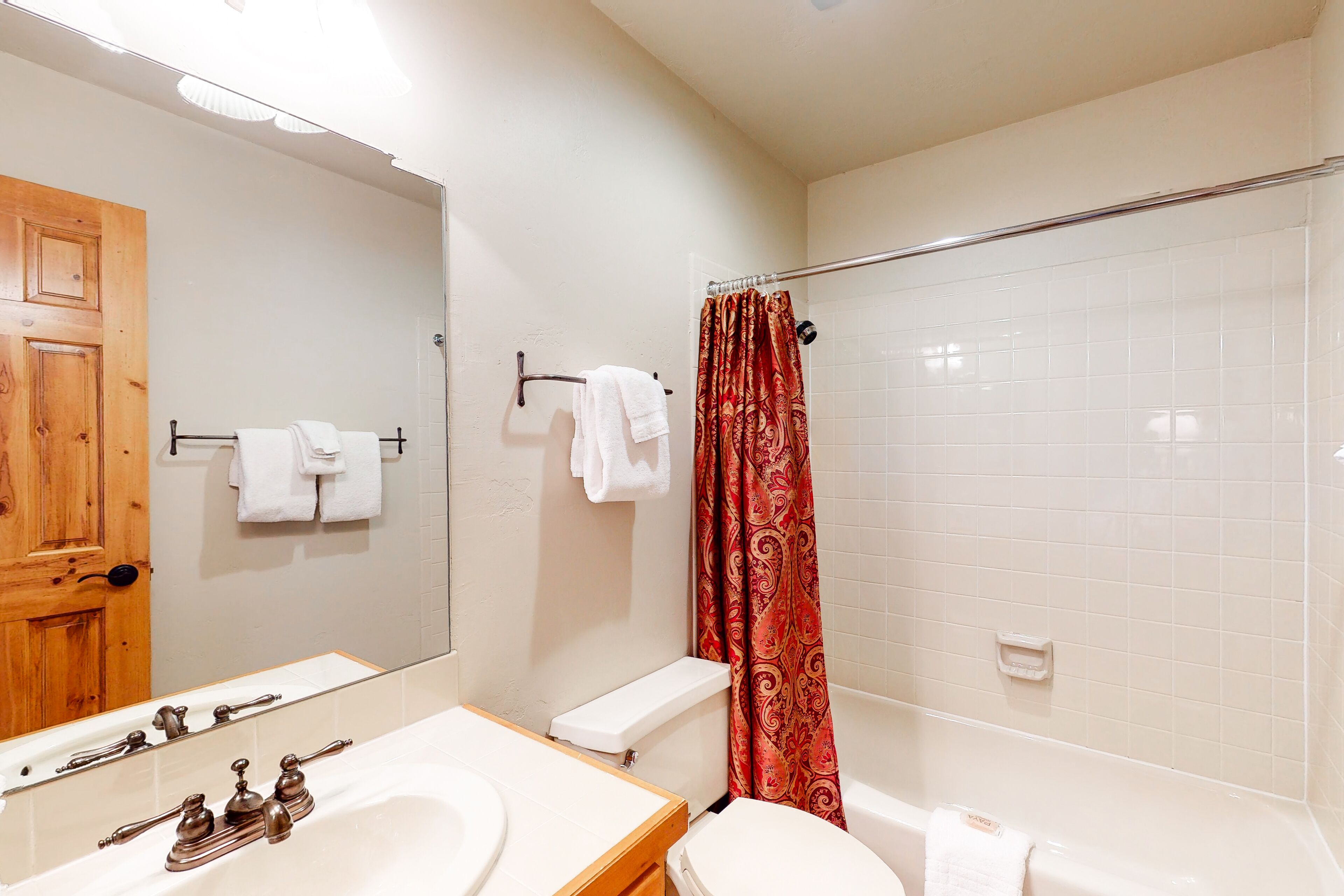 Une salle de bain avec un lavabo blanc, des toilettes, une baignoire et un rideau de douche.