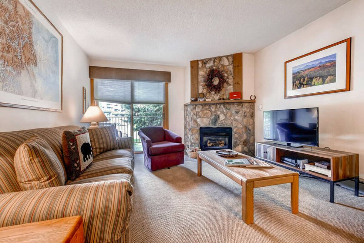 A living room with a stone fireplace, a television, a sofa, and a red armchair.
