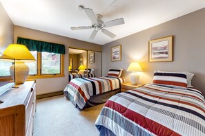 A bedroom with two beds, a ceiling fan, a window with a view, and bedside lamps. - Ski Inn Condos (Steamboat Springs)