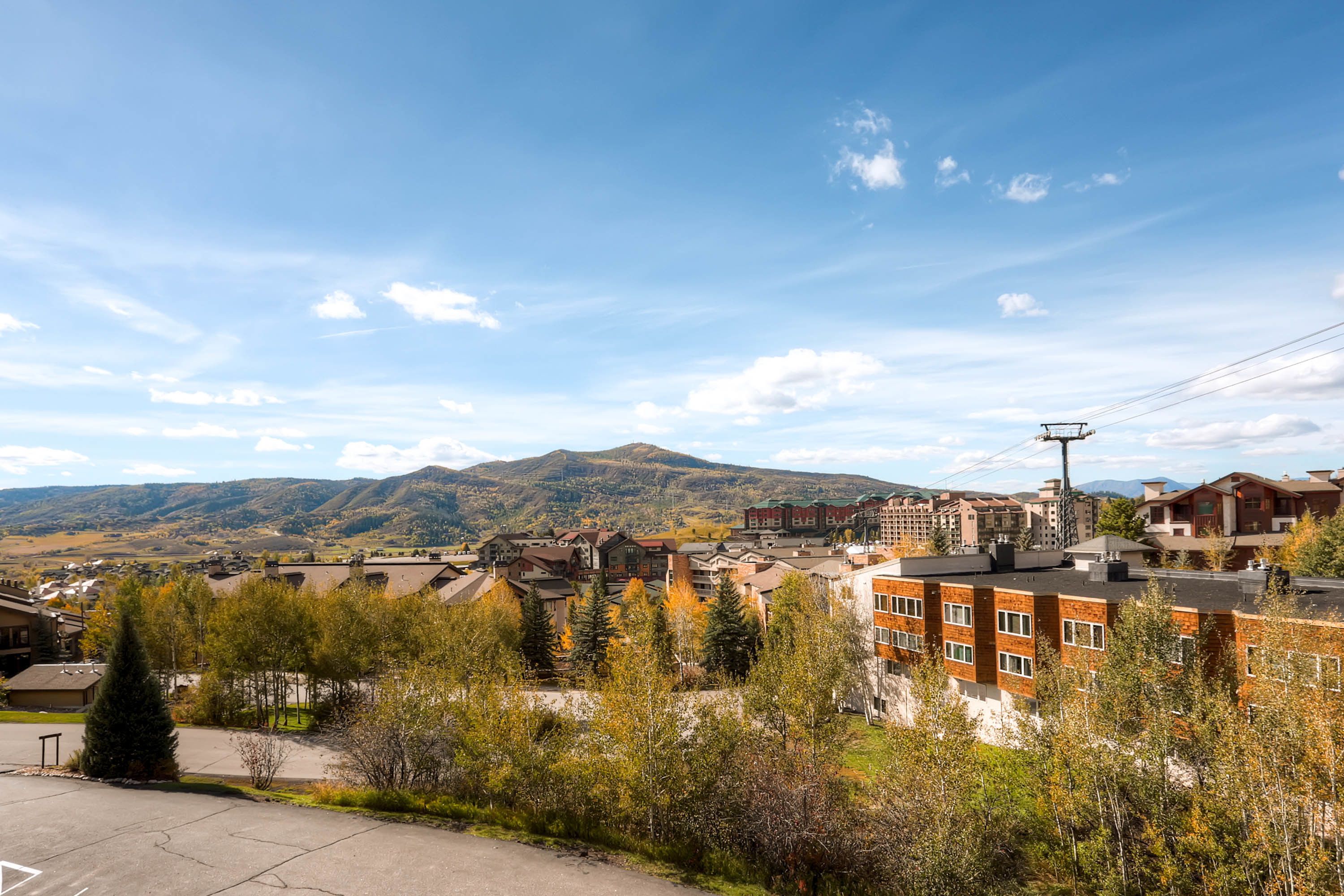 A residential area with a mix of modern and traditional buildings, a clear sky, and distant mountains.