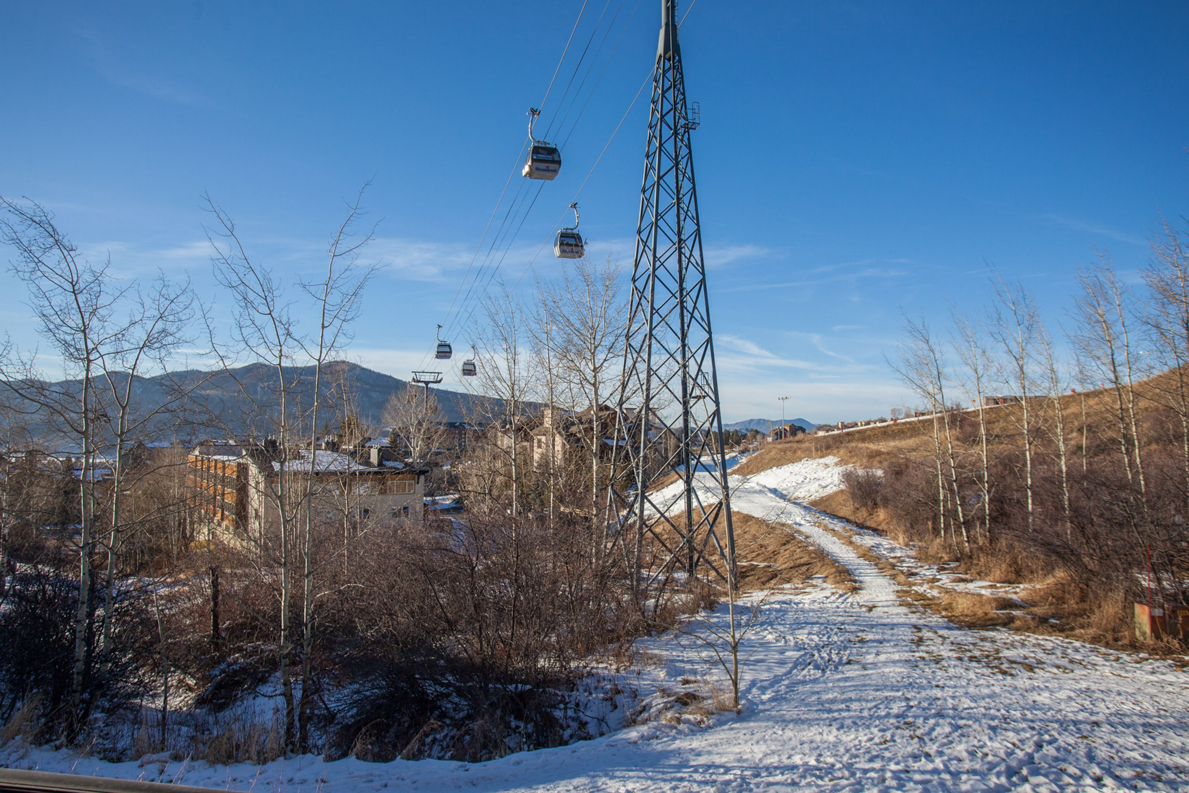 A snowy landscape with a ski lift and a path leading to buildings.