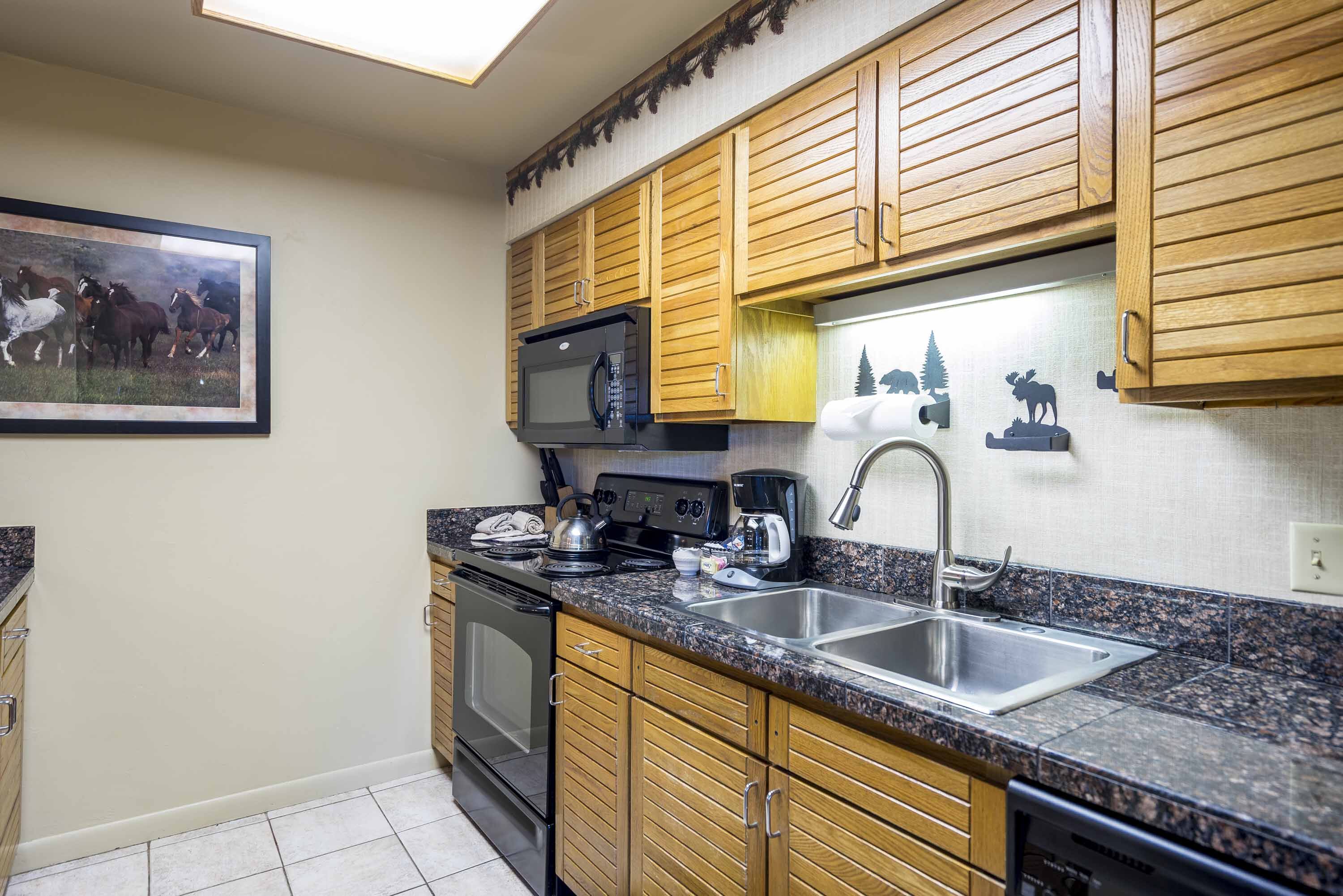 A kitchen with wooden cabinets, a stainless steel sink, a microwave, a stove, and a coffee maker.