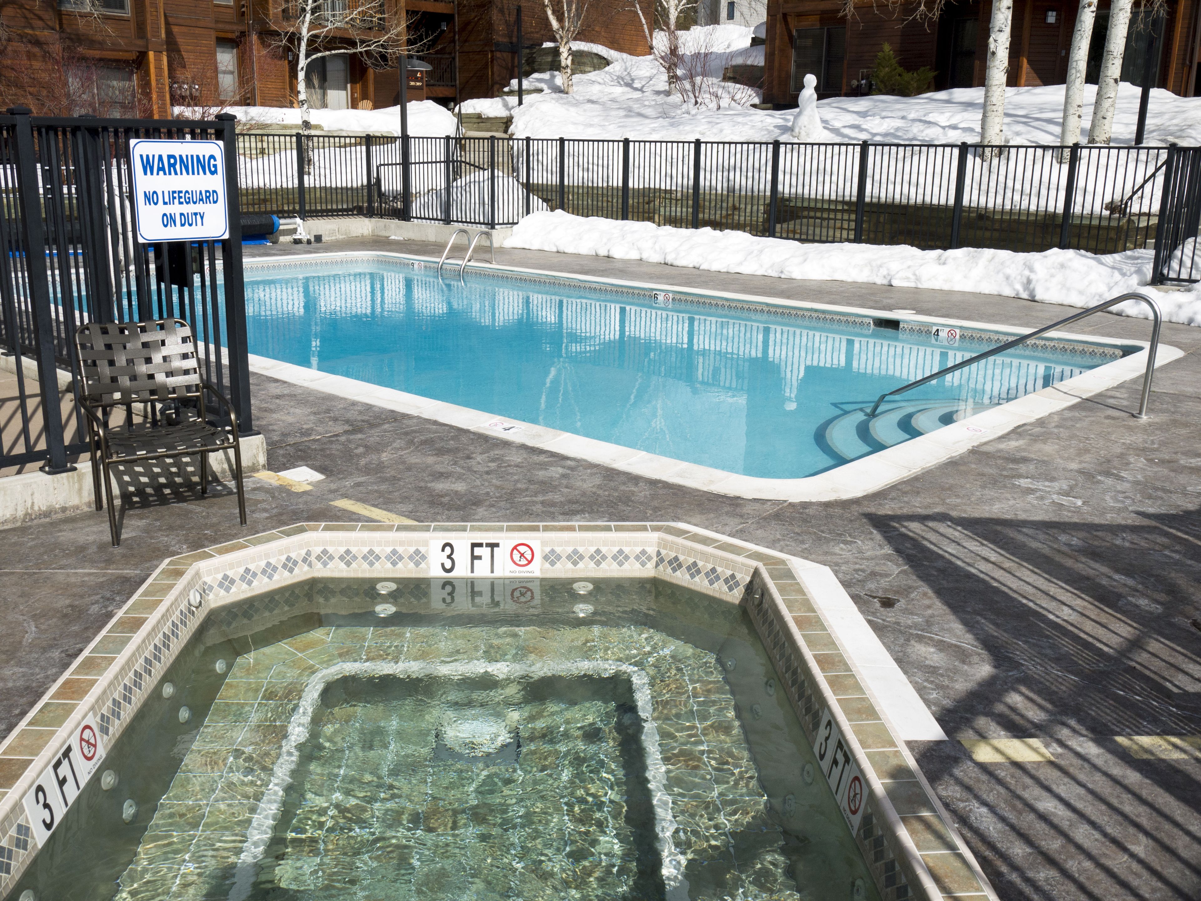 A swimming pool with a 3 ft depth sign and a warning sign stating no lifeguard on duty.