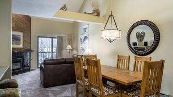 A dining area with a wooden table and chairs, a fireplace, a sofa, and a large mirror on the wall.