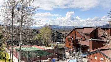 A residential area with a swimming pool, a tennis court, and a view of mountains in the background.