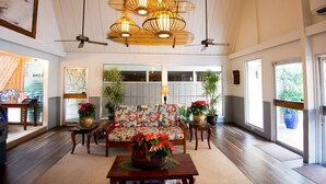 A spacious living area with a sofa, a coffee table with a floral centerpiece, and a ceiling fan.