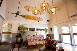 A spacious lobby with a wooden ceiling fan, a sofa with a tropical print, and hanging wicker lamps. - Pacific Marina Inn Airport Hotel (Honolulu)