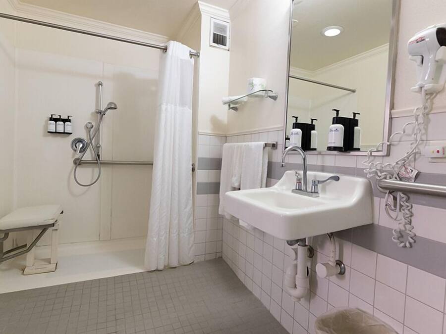 A modern bathroom with a walk-in shower, a sink with a mirror, and a hairdryer mounted on the wall.