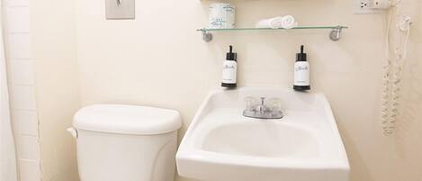 Ein Badezimmer mit Toilette, Waschbecken und einem an der Wand befestigten Fön.