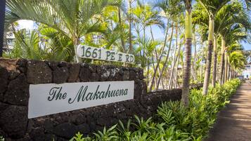 A sign with '1661 PE'ERD' and 'The Makahuena' written on it, surrounded by tropical plants and palm trees.