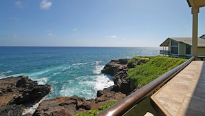 Vista costeira com um edifício ao lado do mar, com varanda e guarda-corpo.
