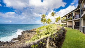 A coastal hotel with a view of the ocean, palm trees, and a grassy area. - Castle at Makahuena at Poipu (Koloa)