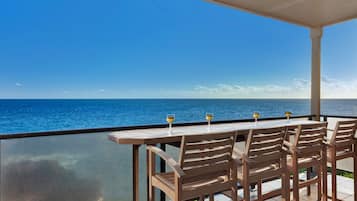 Enjoy a meal with a view on this ocean-facing terrace, featuring a table for four and a glass balustrade.