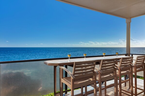 A terrace with a table and chairs overlooking the ocean. - Castle at Makahuena at Poipu (Koloa)
