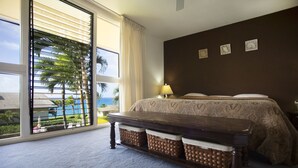 Quarto com uma janela grande, cama, mesa de cabeceira e abajur.