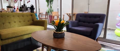 Una sala de estar moderna con un sofá verde, un sillón azul y una mesa de centro de madera con una planta.