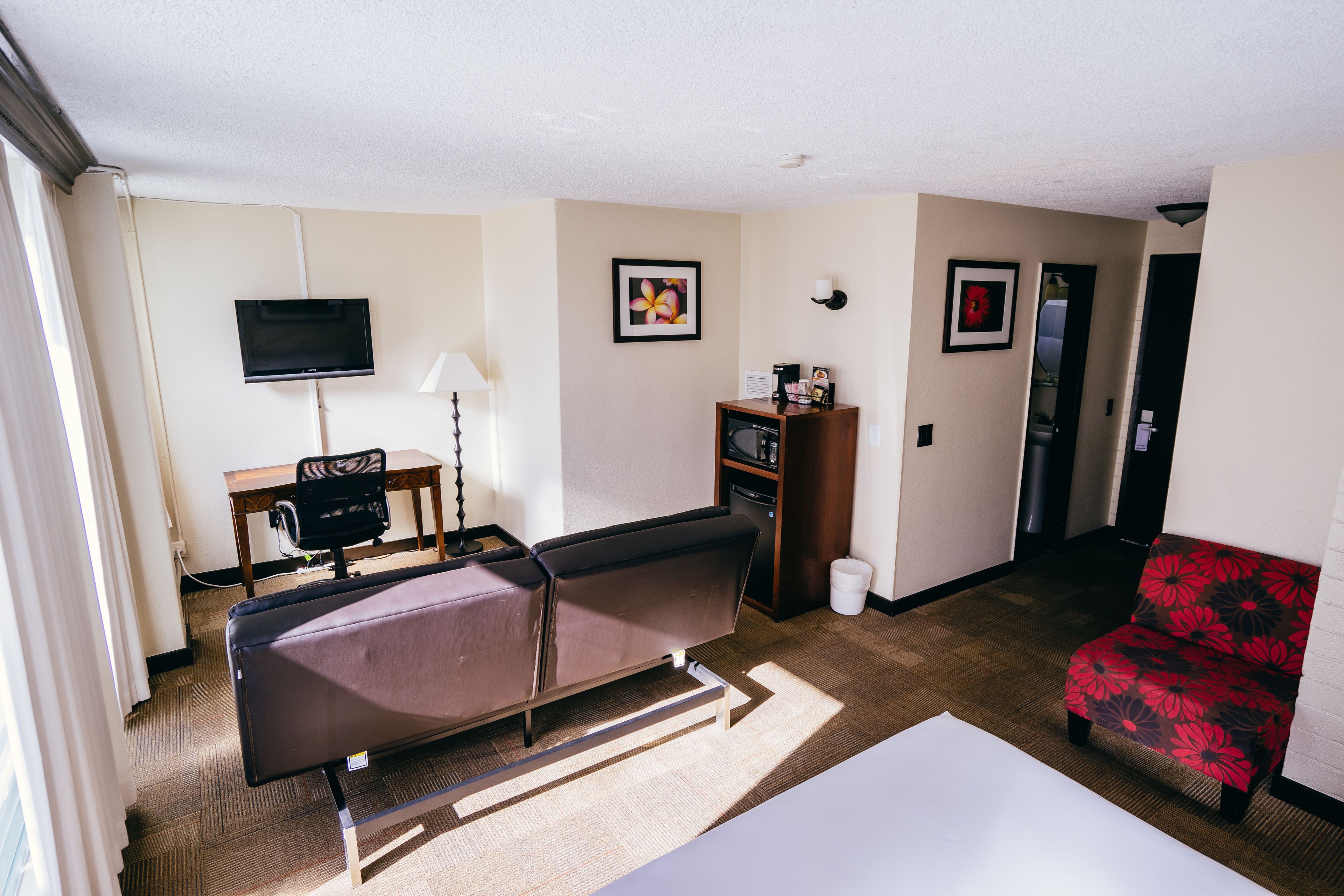 A hotel room with a bed, a TV, a desk, a chair, and a small table.