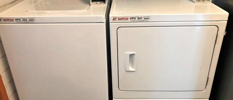 Two white commercial washers with digital displays and control panels.