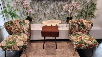 A room with two armchairs, a small wooden side table, and a decorative white object on a white surface.