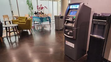 A modern indoor space with a coffee bar, seating area, and an ATM machine.