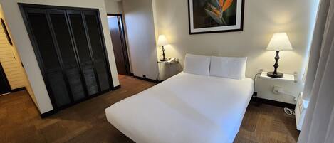 Una camera d'albergo con un letto grande, una scrivania con una lampada, un telefono e un quadro appeso al muro.