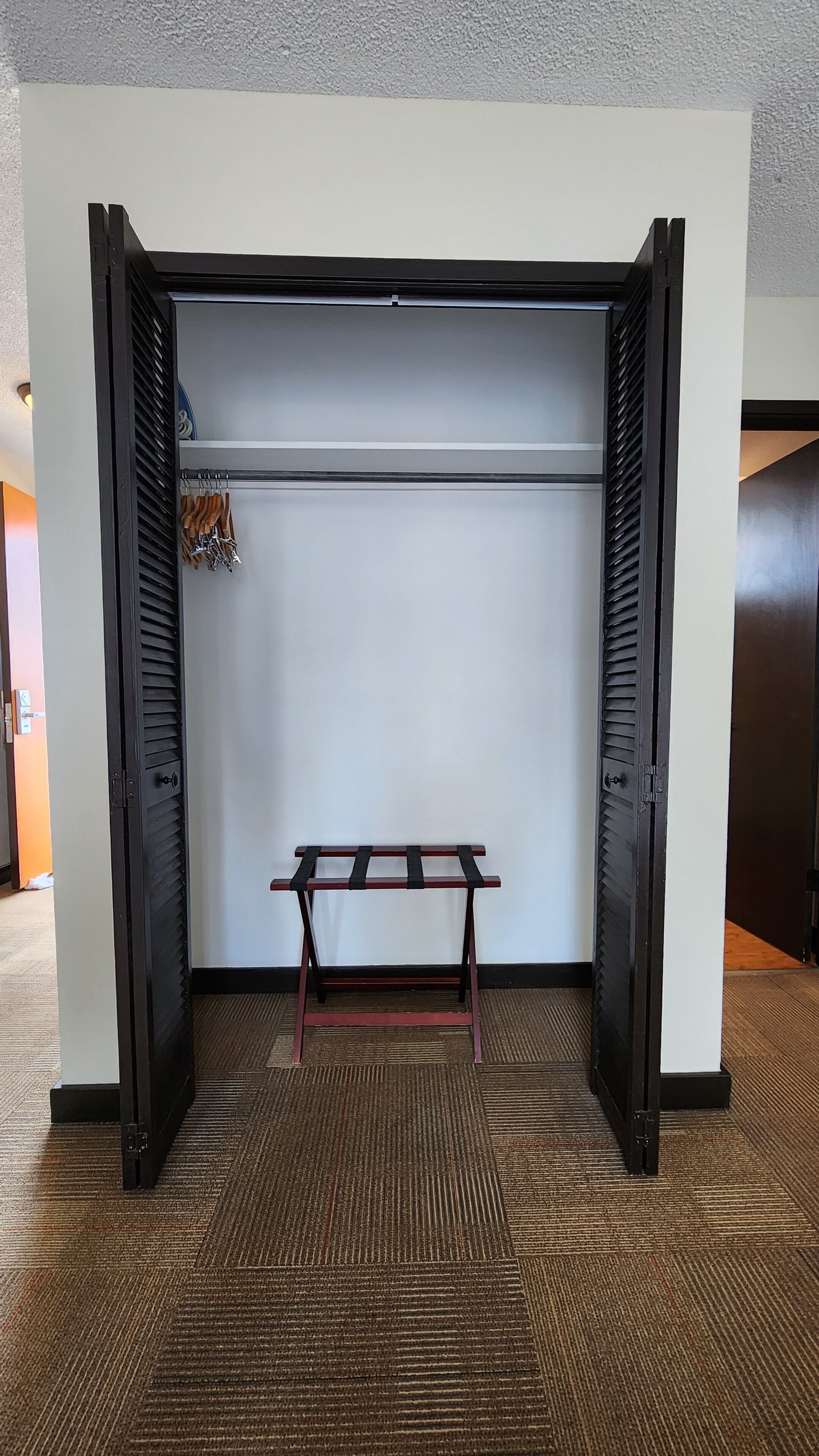 A walk-in closet with a metal rod rack and a bench.