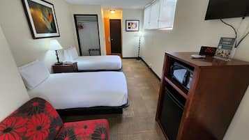 A hotel room with two beds, a desk with a microwave, a TV, and a clock displaying 2:50.