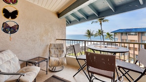 A balcony with wicker furniture, a glass table, and butterfly decorations.