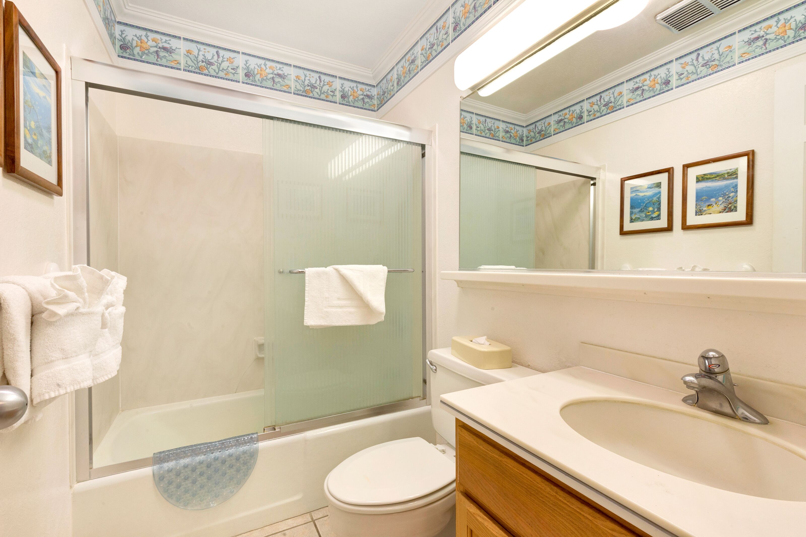 Ein Badezimmer mit einer Glasduschkabine, Toilette, Waschbecken und Spiegel.