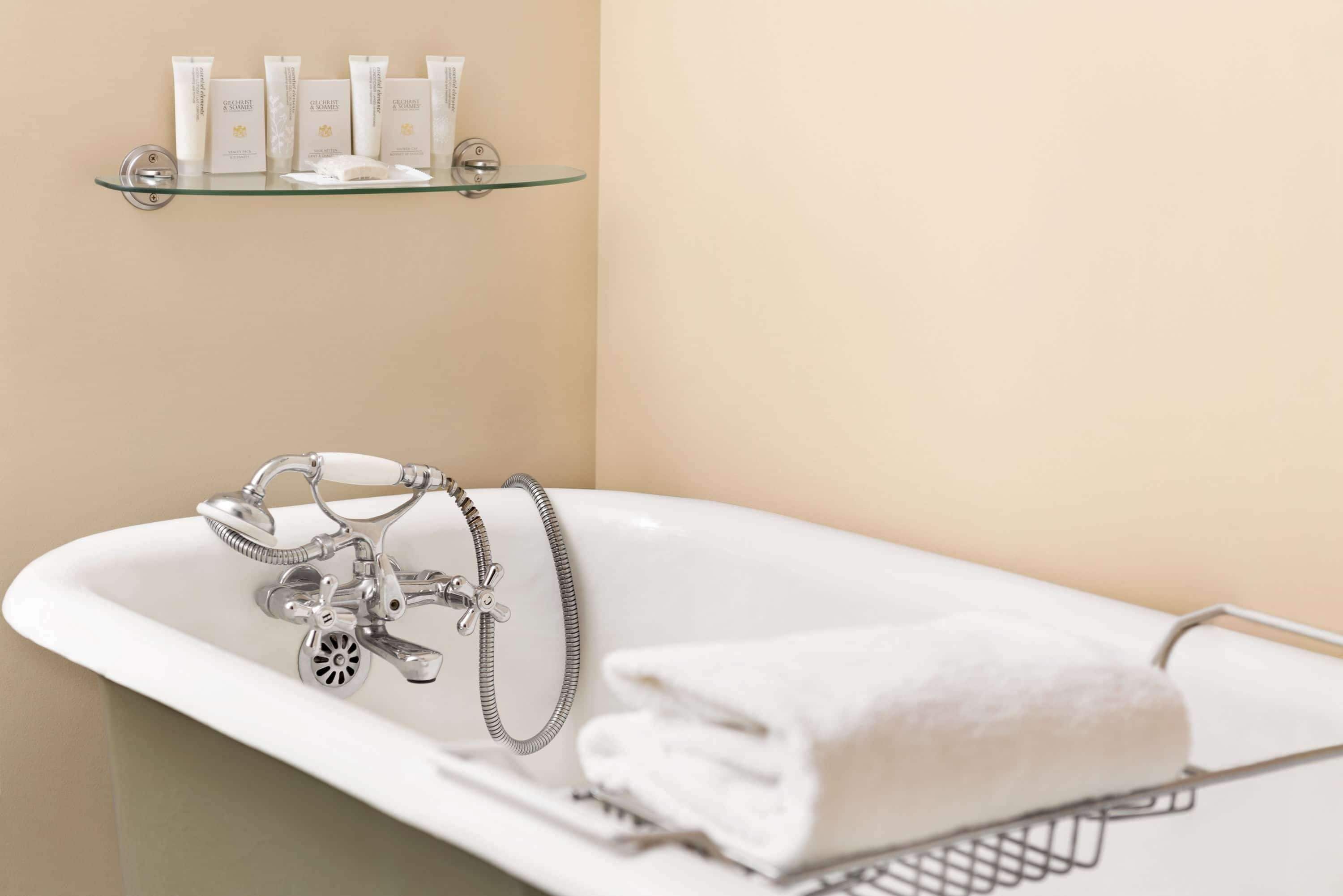 A bathroom with a freestanding bathtub, a towel rack, and a shelf with toiletries.