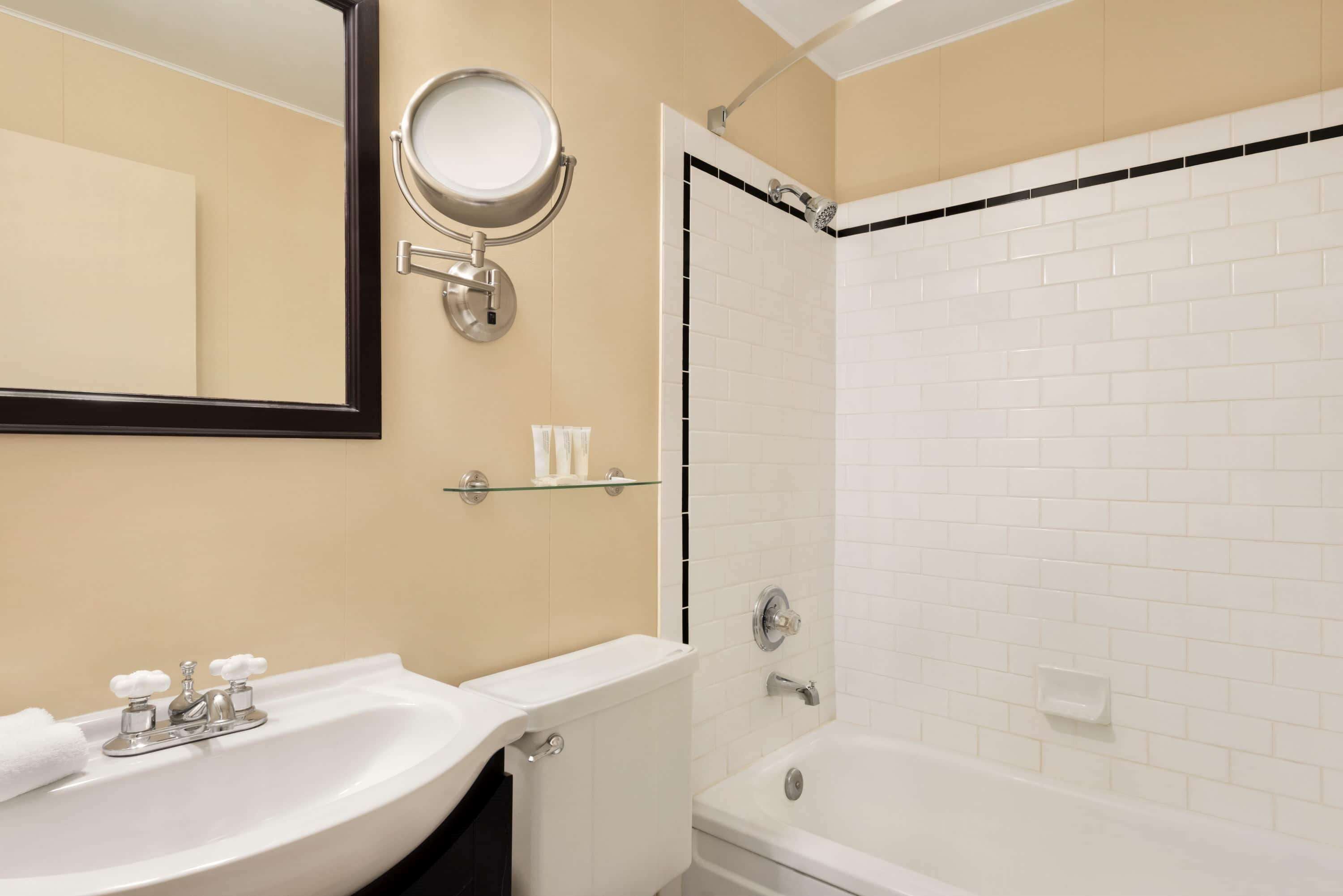 A bathroom with a white sink, mirror, and bathtub.