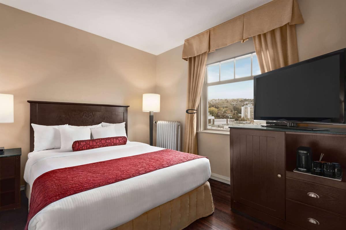 Une chambre d’hôtel avec un grand lit, une télévision, une vue sur la ville et un meuble contenant une machine à café.